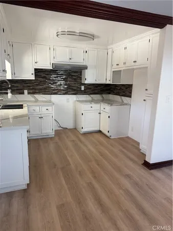 a kitchen with granite countertop a white stove top oven and white cabinets