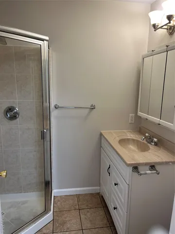 a bathroom with a granite countertop sink a mirror and shower