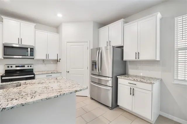 a kitchen with granite countertop a refrigerator sink stove and microwave