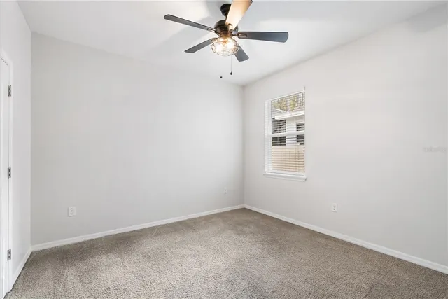 an empty room with a window and a fan
