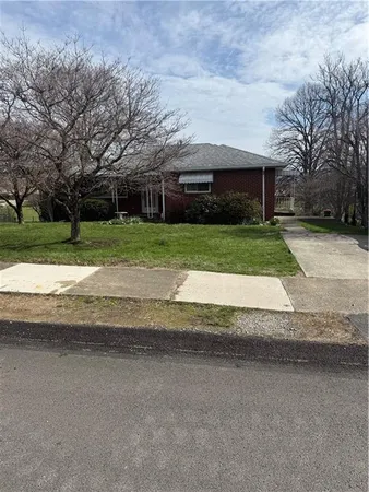 a front view of a house with a yard and a large tree