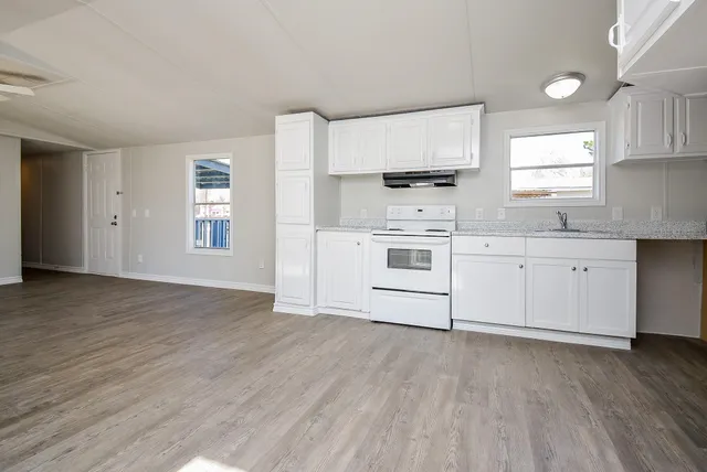 a kitchen with stainless steel appliances a white cabinets and wooden floor