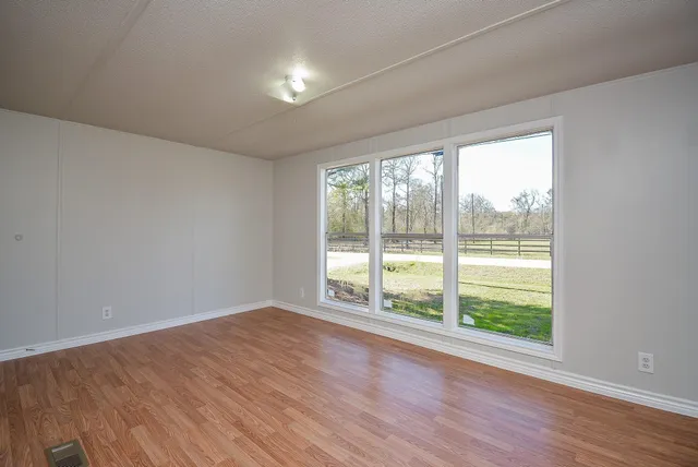 a view of an empty room with wooden floor and a window