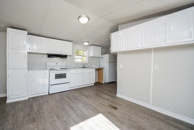 a kitchen with cabinets stainless steel appliances and wooden floor