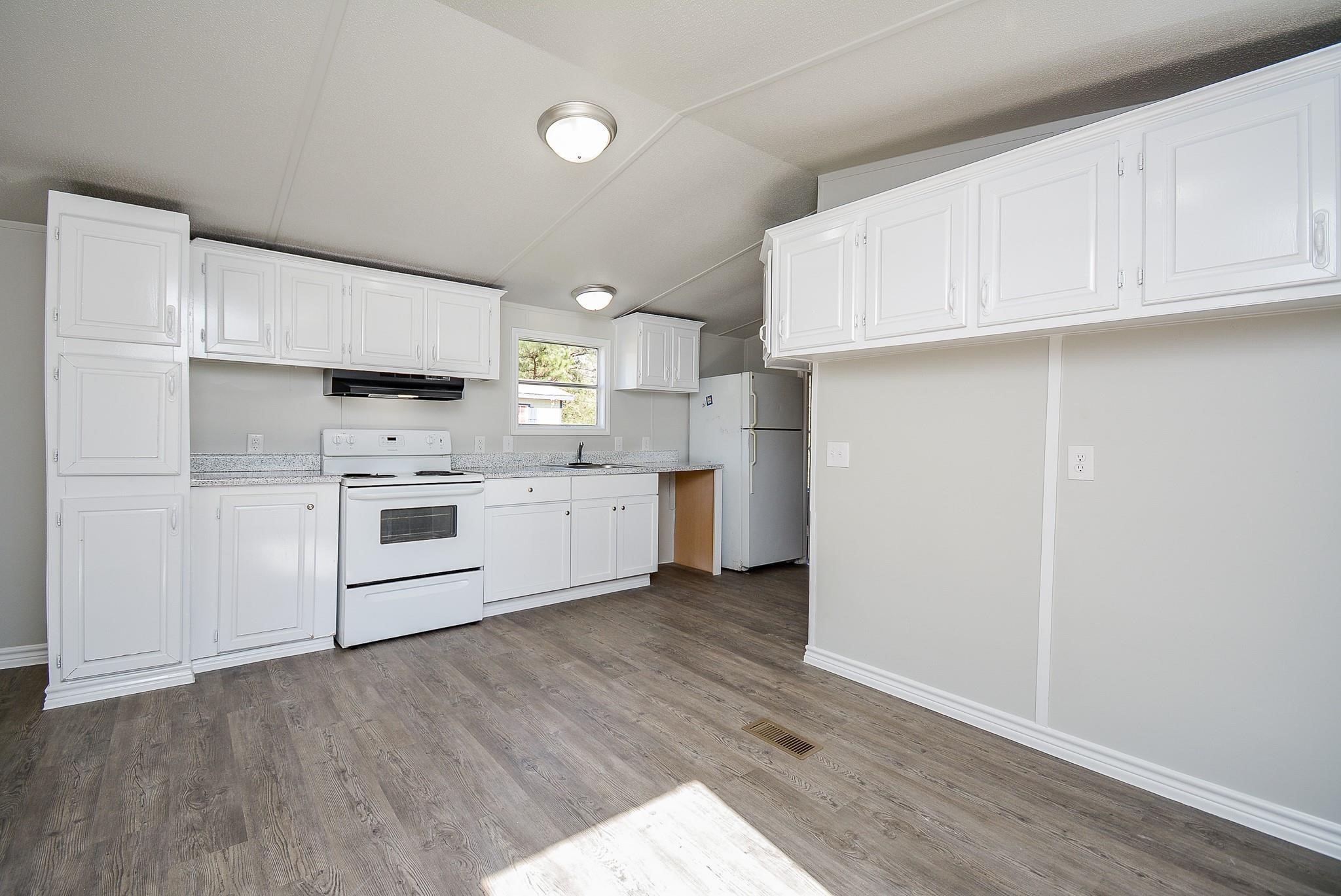 12561 Roy Harris Loop Conroe, TX 77306 - Photo 2 of 31 a kitchen with cabinets stainless steel appliances and wooden floor