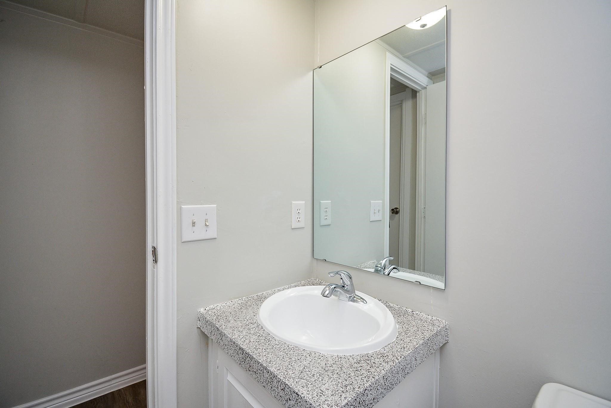 12561 Roy Harris Loop Conroe, TX 77306 - Photo 23 of 31 a bathroom with a granite countertop sink and a mirror