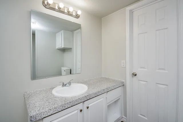 a bathroom with a granite countertop sink and a mirror