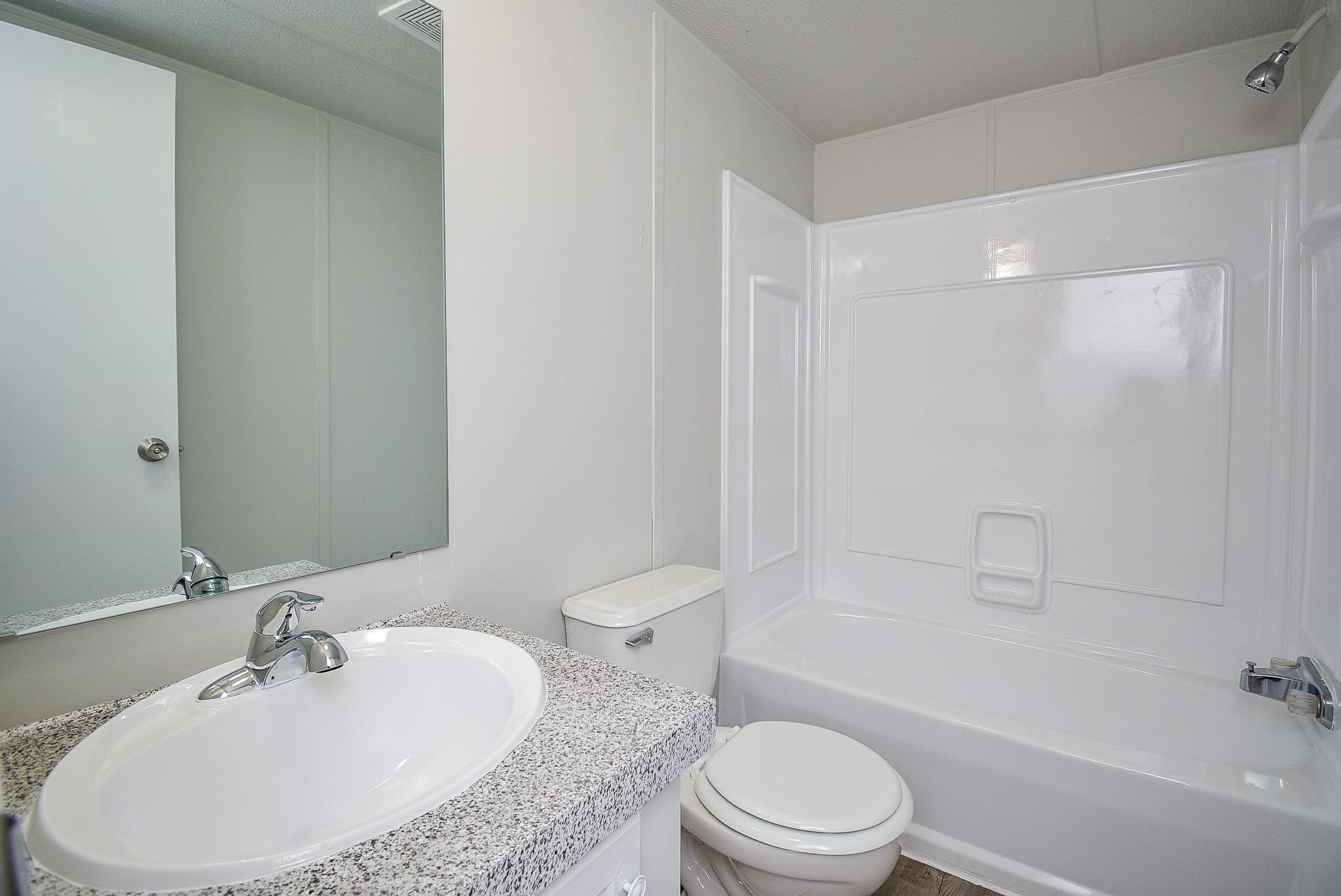 12561 Roy Harris Loop Conroe, TX 77306 - Photo 28 of 31 a bathroom with a granite countertop sink toilet a mirror and shower