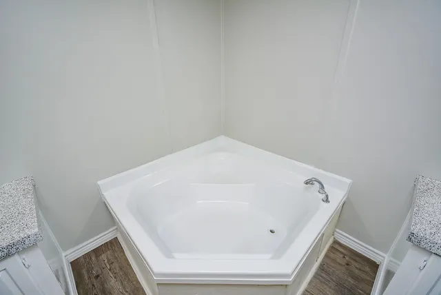 a bathroom with a white tub shower sink and mirror