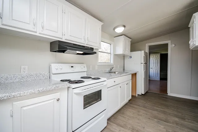 a kitchen with granite countertop white cabinets and white appliances