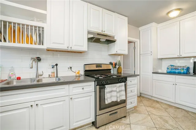 a kitchen with stainless steel appliances granite countertop white cabinets and a stove a oven with white countertops