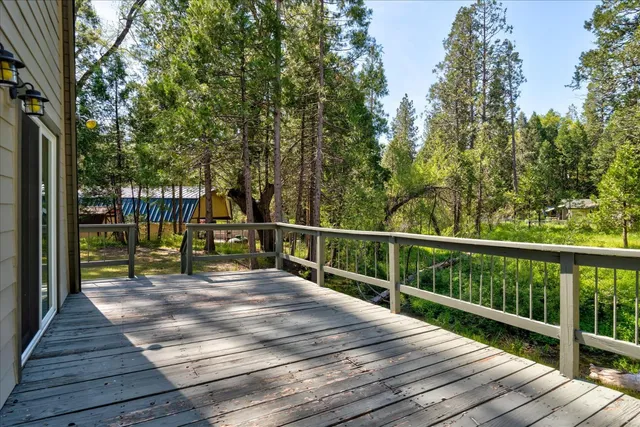 a view of a deck with wooden floor and fence with a trees