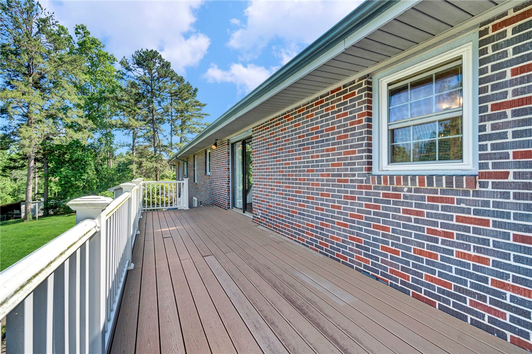 7876 Highway 11 Walhalla, SC 29691 - Photo 8 of 35 A spacious wooden deck provides generous outdoor living, extending from the brick-clad structure into a tree-lined setting.
