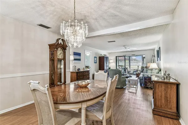 a dining room with wooden floor a chandelier a wooden table and chairs