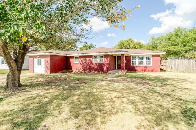a view of a house with a large tree and a yard