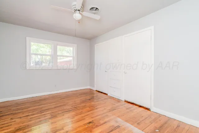 a view of empty room with wooden floor and fan