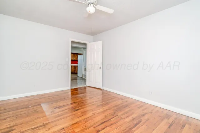 an empty room with wooden floor and fan