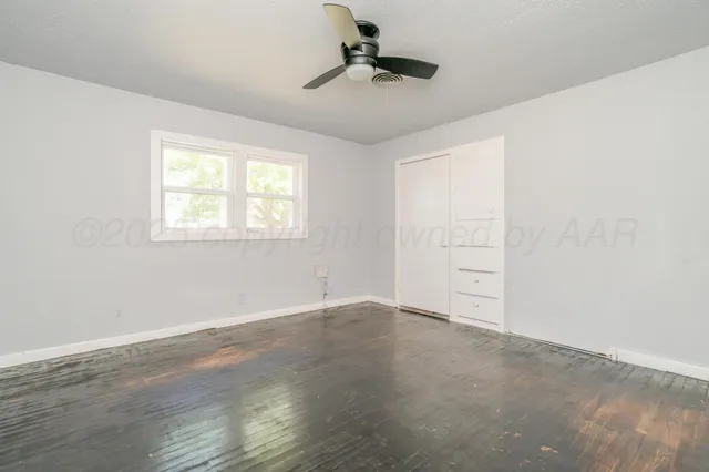 an empty room with windows and ceiling fan