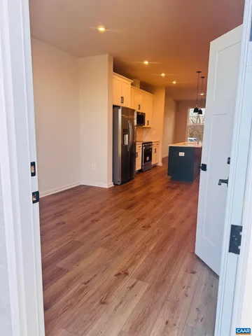 a view of a big room with wooden floor and a refrigerator