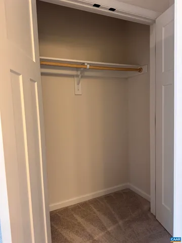 a view of a hallway with wooden floor and a bathroom
