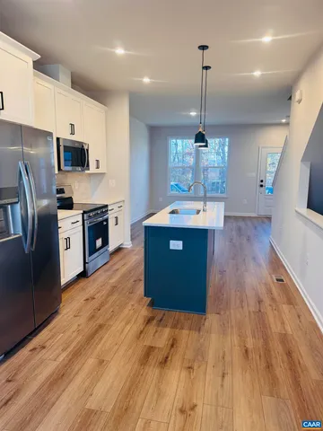 a kitchen with stainless steel appliances granite countertop a refrigerator a stove top oven a sink dishwasher and wooden floor