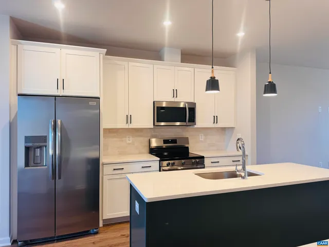 a kitchen with stainless steel appliances a sink a stove a refrigerator a center island and cabinets