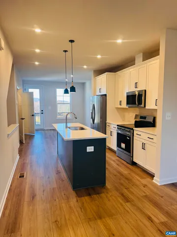 a kitchen with stainless steel appliances a refrigerator sink and wooden floor