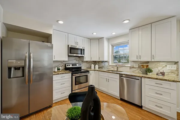 a kitchen with white cabinets stainless steel appliances and a sink