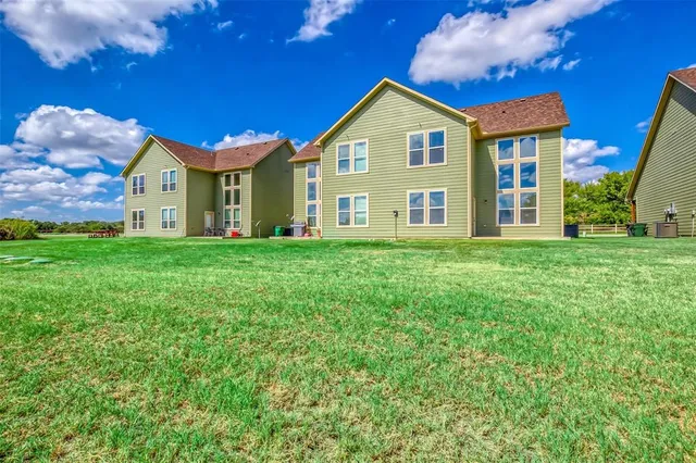 a view of a house with a big yard and large trees