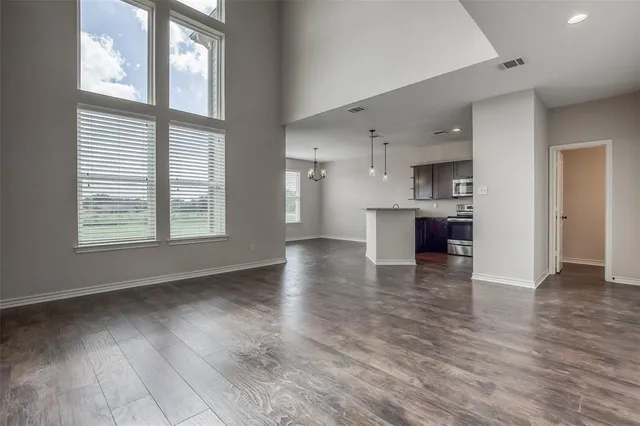a view of a kitchen and an empty room with wooden floor and a kitchen
