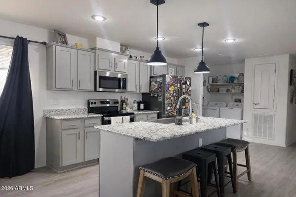 a kitchen with kitchen island granite countertop a sink a counter space appliances and cabinets
