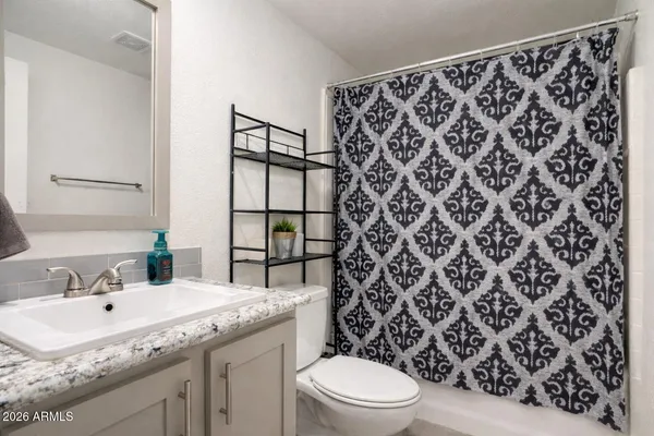 a bathroom with a granite countertop sink and a toilet