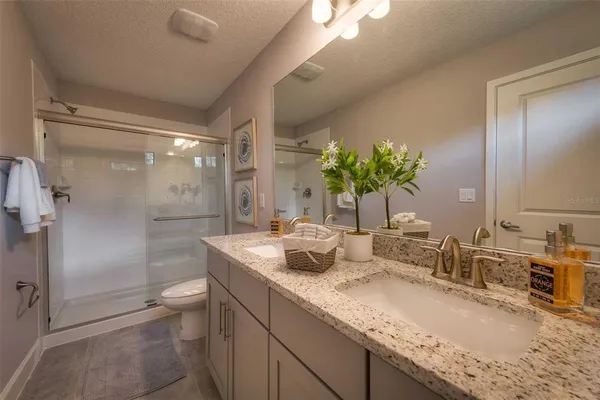 a bathroom with a granite countertop sink a toilet and shower