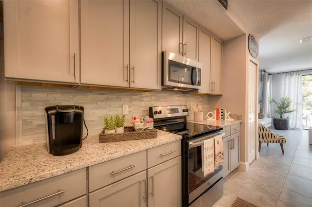 a kitchen with granite countertop white cabinets and stainless steel appliances