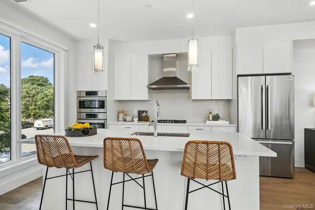 a kitchen with stainless steel appliances granite countertop a stove a refrigerator a dining table and chairs with wooden floor