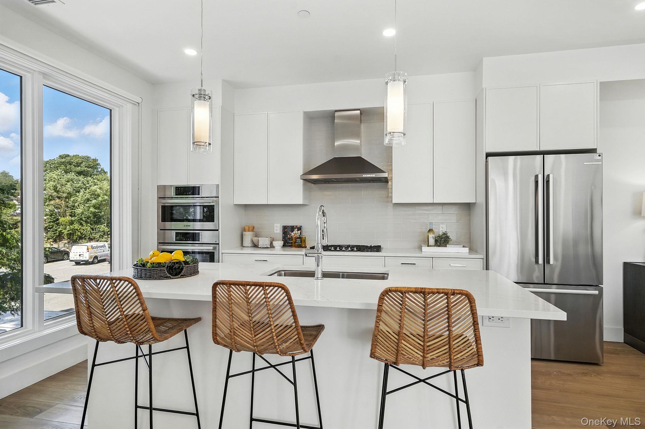 402 Halstead Avenue, Unit 204 Harrison, NY 10528 - Photo 6 of 15 a kitchen with stainless steel appliances granite countertop a stove a refrigerator a dining table and chairs with wooden floor