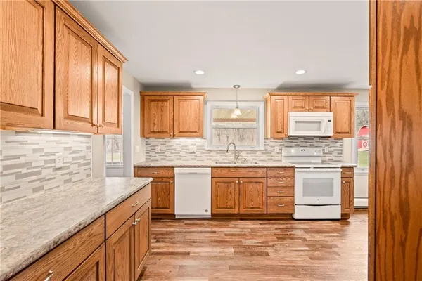 a kitchen with granite countertop a refrigerator a sink and wooden cabinets