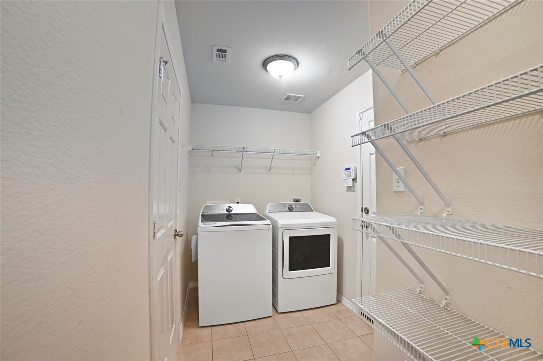 316 Housefinch Loop Leander, TX 78641 - Photo 31 of 37 Laundry room with shelving and full-size washer/dryer connections.