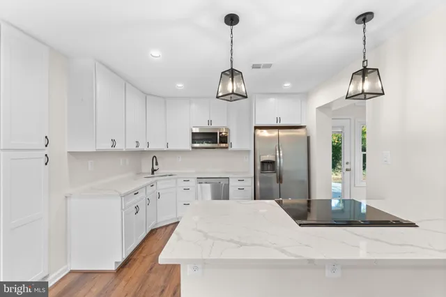 a kitchen with kitchen island stainless steel appliances sink cabinets and wooden floor