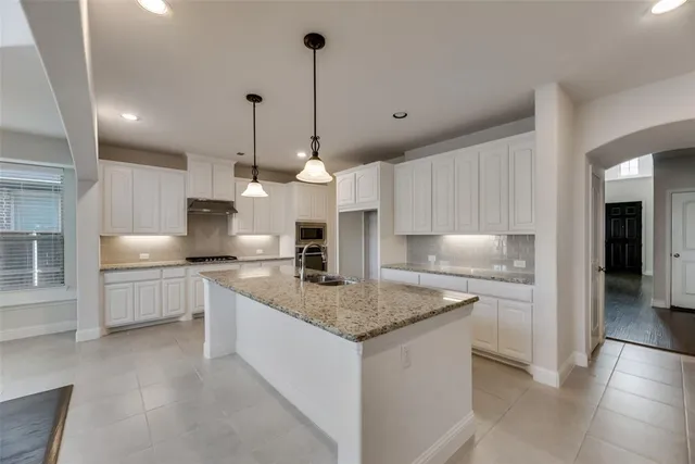 a kitchen with white cabinets and sink