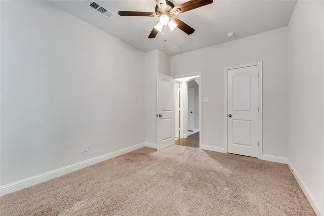 a view of an empty room and chandelier fan