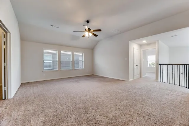 an empty room with chandelier fan and windows