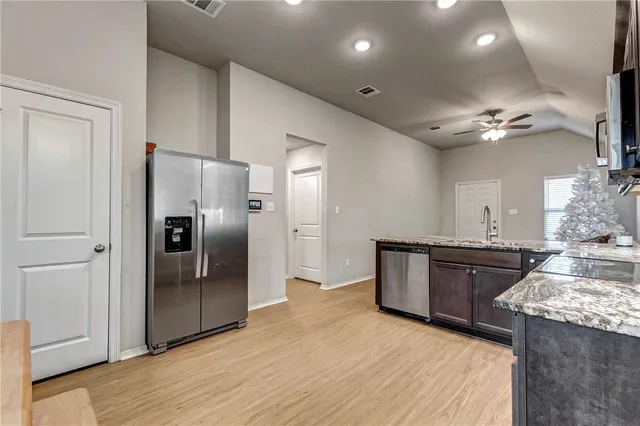 a large kitchen with stainless steel appliances granite countertop a refrigerator a sink a stove and oven