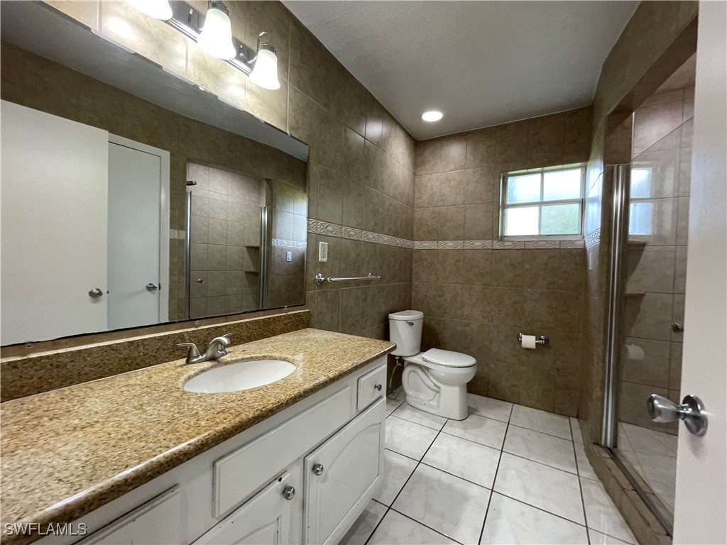 200 Ridgewood Avenue Clewiston, FL 33440 - Photo 35 of 50 a bathroom with a granite countertop sink a toilet a mirror and shower