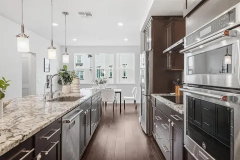 a kitchen with stainless steel appliances granite countertop a sink a stove and a wooden floors