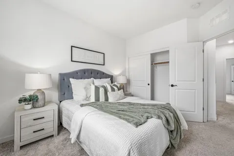 a bedroom with a bed and a lamp on dresser