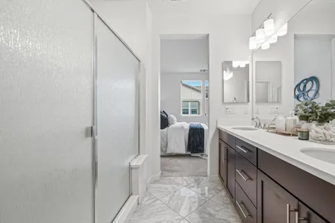 a spacious bathroom with a double vanity sink a mirror and a shower