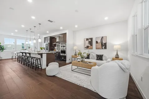 a living room with furniture a wooden floor and kitchen view