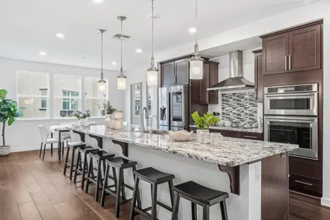 a kitchen with granite countertop a table chairs stainless steel appliances and cabinets