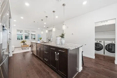 a large kitchen with stainless steel appliances a large counter top a stove a chimney a sink and a refrigerator